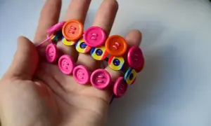 Kolorowa bransoletka z guzików na dłoni. Oto, co można zrobić z guzików – kreatywna biżuteria DIY.