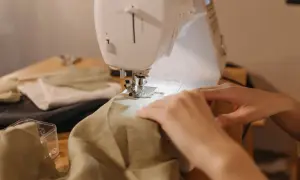 Dłonie prowadzą tkaninę pod igłę maszyny do szycia. Może to być powód, dlaczego maszyna nie łapie dolnej nici.