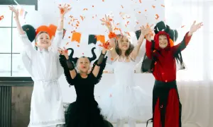Dzieci w strojach aniołów i diabła rzucają konfetti. Inspiracja, jak zrobić strój na Halloween dla dziecka.