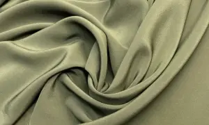 Miękka, oliwkowa tkanina układa się w eleganckie fałdy, tworząc wrażenie płynności. To idealny materiał na sukienkę.