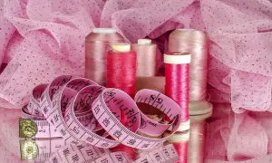 Różowy, przewiewny materiał na lato, nici i miarka krawiecka. Idealne do letnich kreacji.