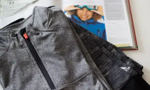 Szara bluza sportowa z zamkiem, obok otwarta książka z narciarką. Czy poliamid materiał czy oddycha?