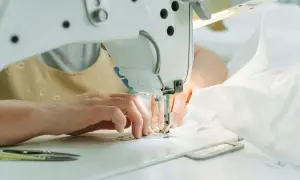 Ręce szyjące na maszynie. Zastanawiasz się, czym zastąpić olej do maszyny do szycia? Sprawdź nasze porady!