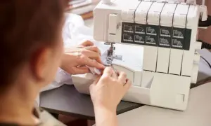 Kobieta używa maszyny do obrębiania brzegów tkaniny, tworząc delikatne wykończenie.