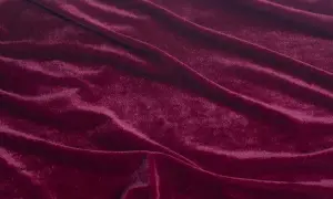 Głęboki, burgundowy materiał o miękkiej, połyskującej powierzchni, podobny do aksamitu, tworzy eleganckie fałdy.
