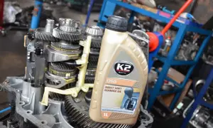Butelka oleju do skrzyni biegów DSG na tle mechanizmu skrzyni biegów.
