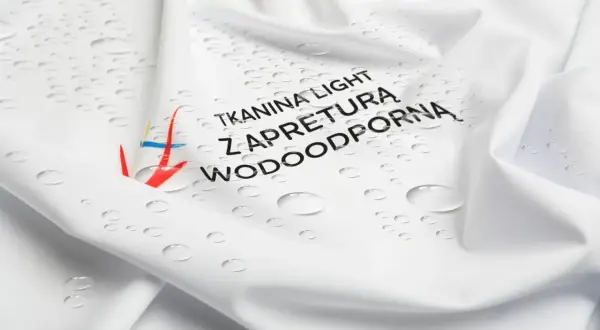 Biała tkanina z kropelkami wody i napisem "Tkanina light z apreturą wodoodporną". Idealna na deszczowe dni.