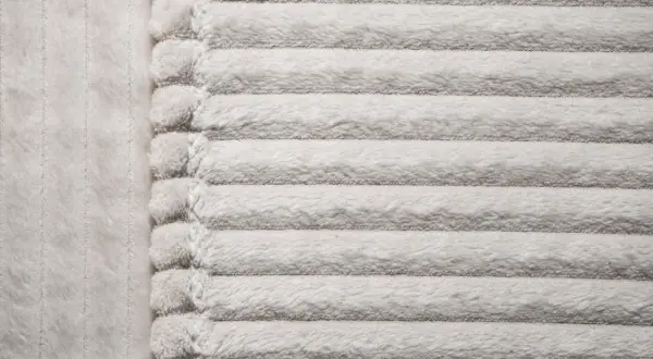 Miękki, prążkowany materiał mikrofibra w jasnym kolorze.