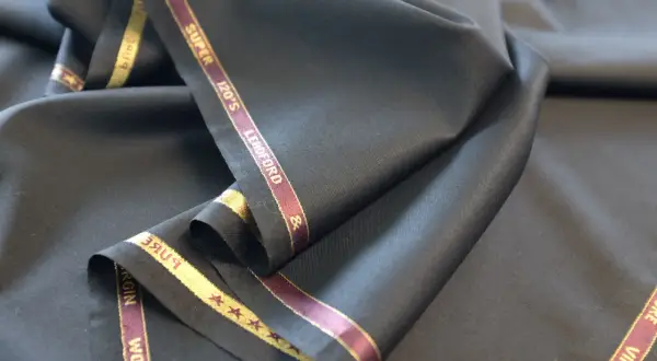 Elegancka, czarna wełna z metką "Super 120's Virgin Wool". Idealna na garnitur.