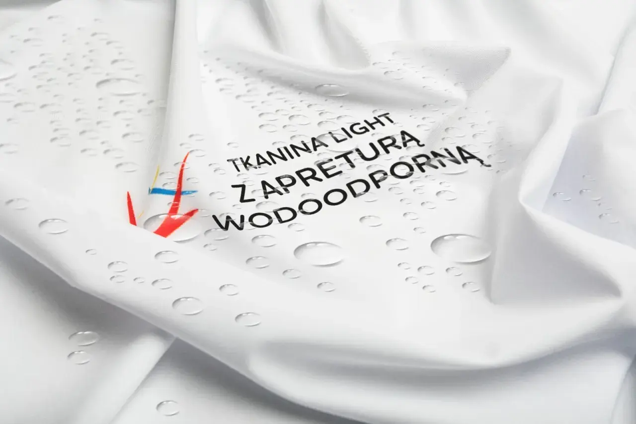 Biała tkanina z kropelkami wody i napisem "Tkanina light z apreturą wodoodporną". Idealna na deszczowe dni.