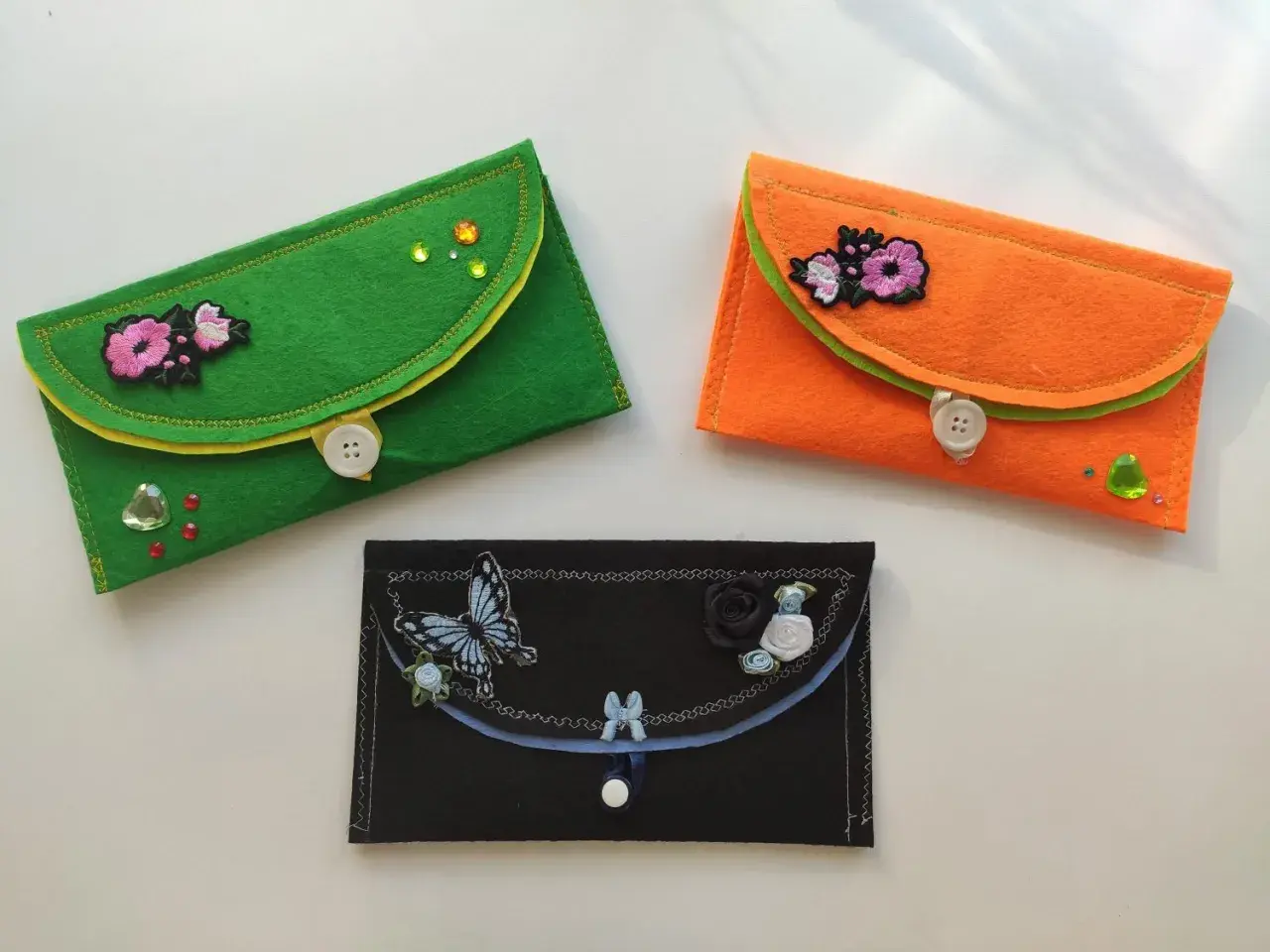 Kolorowe etui z filcu, ozdobione haftowanymi kwiatami i motylami. Idealne do nauki szycia dla dzieci.